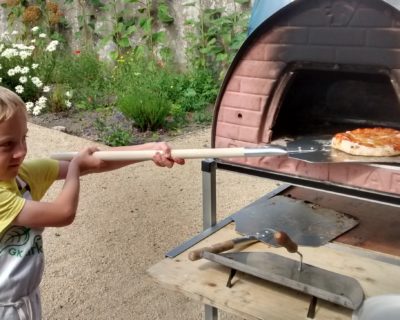 boy putting pizza into wood oven