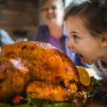 Small girl having fun while about to bite into a turkey