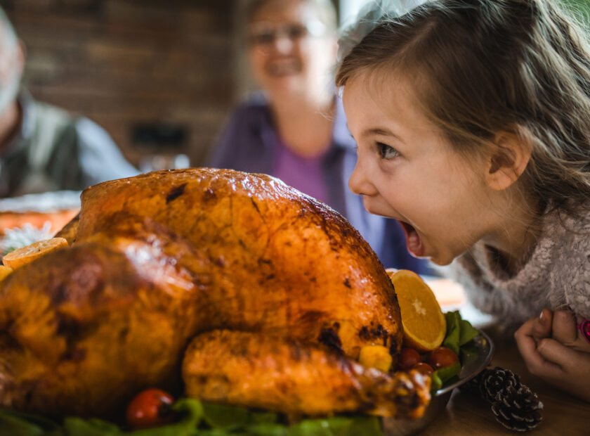 Small girl having fun while about to bite into a turkey