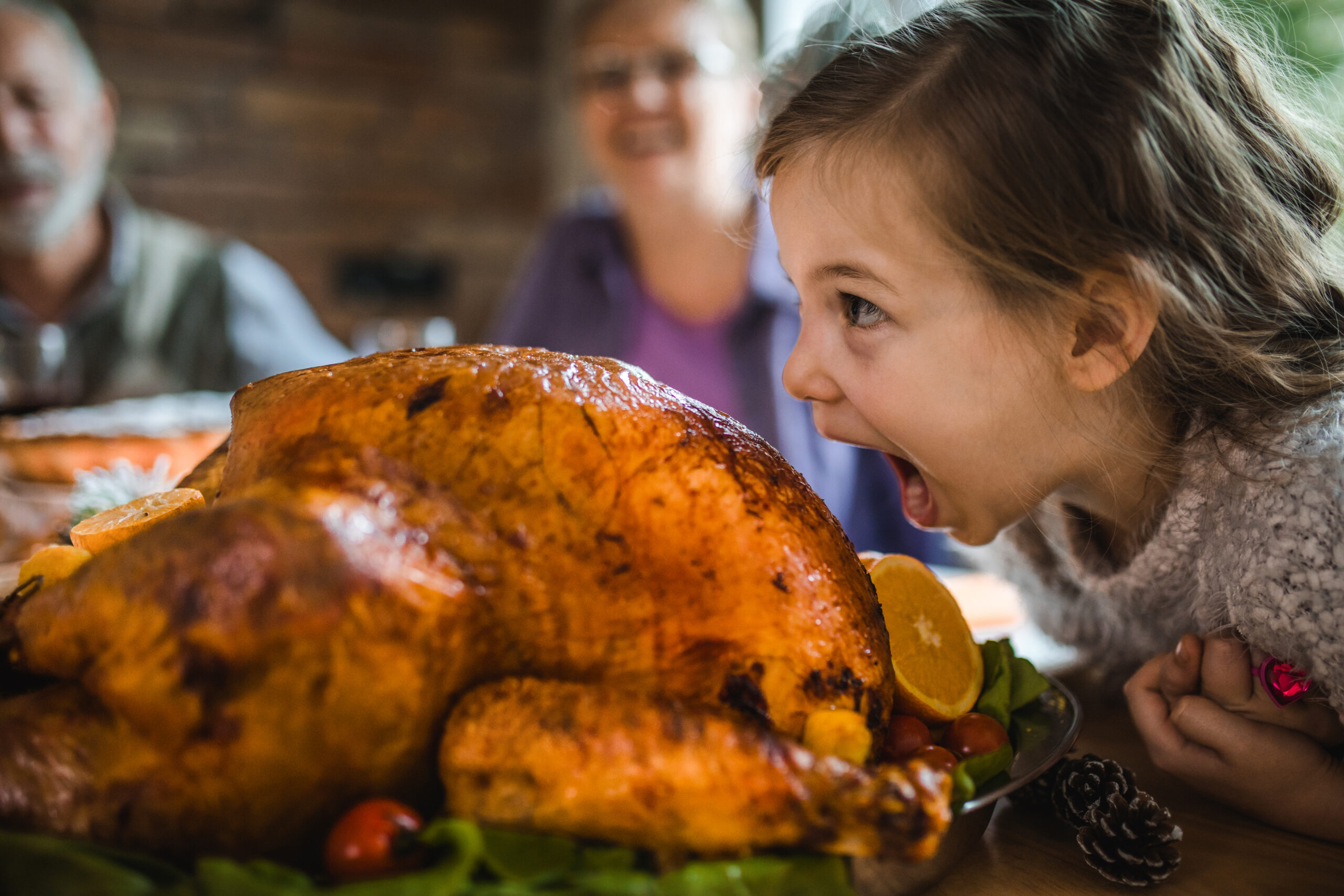 Small girl having fun while about to bite into a turkey