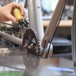 mechanic in a bicycle repair shop oiling the chain of a bike