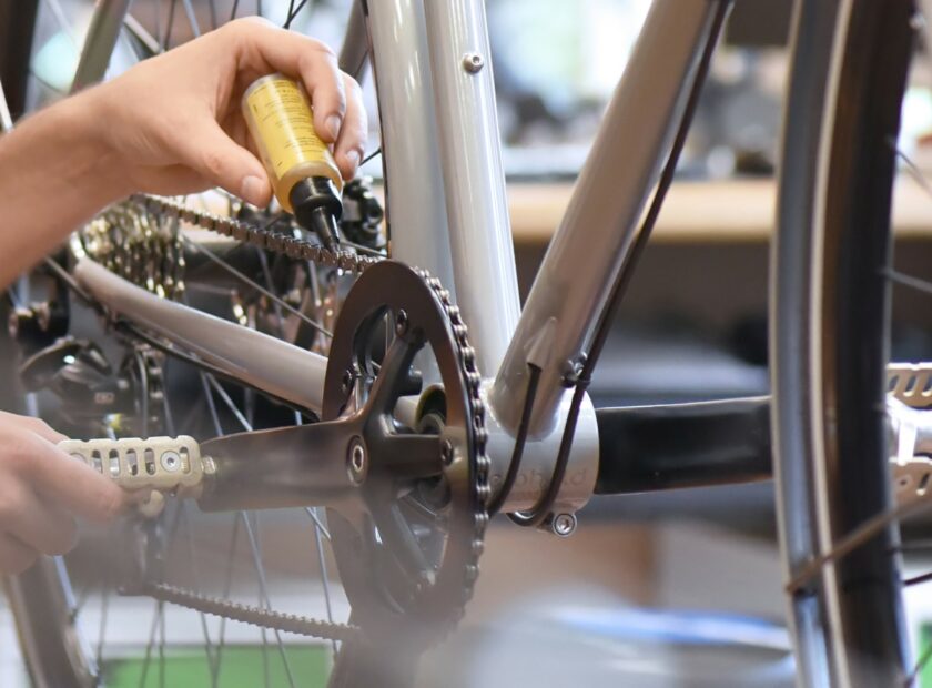 mechanic in a bicycle repair shop oiling the chain of a bike