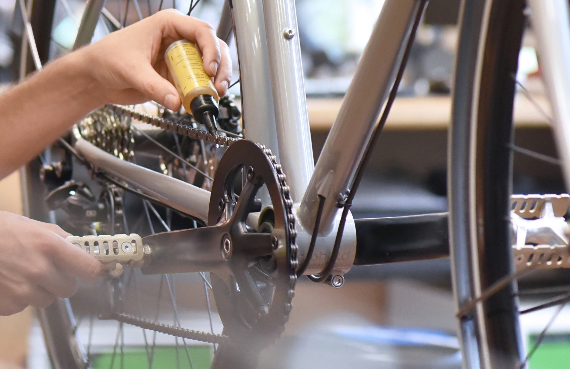 mechanic in a bicycle repair shop oiling the chain of a bike