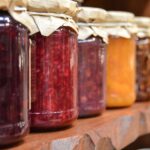 Jars of jam on a wooden shelf.